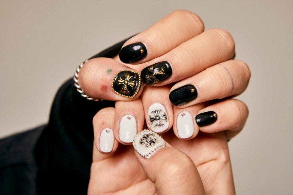 black and white short nails with gold cross and rhinestone nail design