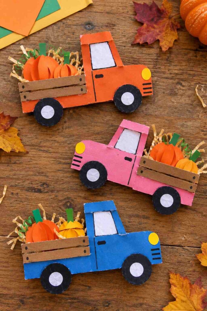21 Easy & Creative Fall Crafts for Kids to Make at Home 20 18. Paper Pumpkin Harvest Truck Craft for Kids
Create a cute little fall pickup truck using construction paper and recycled cardboard! Fill its tiny truck bed with colorful paper pumpkins and shredded paper to give it a fun autumn harvest look. It's a lovely craft for kids who enjoy vehicles and fall decorations.
Materials Needed:
- Orange, blue, pink, brown, and green construction paper
- Recycled cardboard
- White and black paper scraps
- Glue stick
- Child-safe scissors
- Black marker
- Yellow paper
How to Make It:
1. Draw a simple pickup truck shape on cardboard and cut it out. Cover it with your favorite colored paper.
2. Cut out two large black paper circles for wheels and add smaller white circles in the middle.
3. Make a square window using white paper and draw the door and headlights with a marker.
4. Add two or three narrow brown cardboard strips to create the truck bed.
5. Cut small orange paper pumpkins, add green stems, and place them in the back of the truck.
6. Finish with a few thin yellow paper strips to look like straw.
Quick Tip: Use an old cereal box for the truck base. Slightly uneven paper pumpkins and hand-cut wheels make each truck look unique.