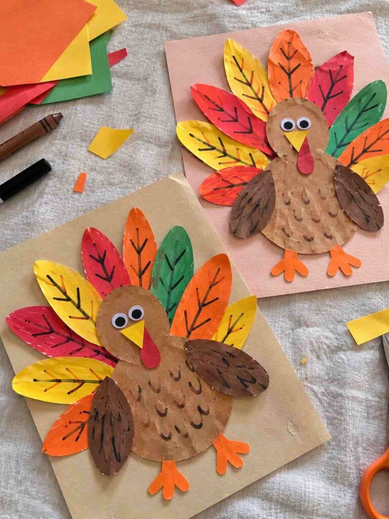 21 Easy & Creative Fall Crafts for Kids to Make at Home 23 21. Colorful Paper Turkey Craft for Kids
Make a cheerful Thanksgiving turkey using colorful construction paper! Kids can create a fan of bright autumn feathers and give their turkey a funny little face. It's a simple paper craft for a fall afternoon at home or in the classroom.
Materials Needed:
- Brown, red, orange, yellow, and green construction paper
- White paper
- Googly eyes
- Glue stick
- Child-safe scissors
- Black and brown markers
How to Make It:
1. Cut 5–7 long leaf-shaped feathers from colorful paper. They don't need to be exactly the same size.
2. Draw simple feather lines with a marker and glue the feathers in a fan shape.
3. Cut a round brown head and a larger oval body. Glue them over the bottom of the feathers.
4. Add googly eyes, a small yellow triangle beak, and a red paper wattle.
5. Cut two simple orange feet and glue them underneath the body.
Quick Tip: Let kids choose their own feather colors and draw silly expressions. Each turkey will have its own personality!
