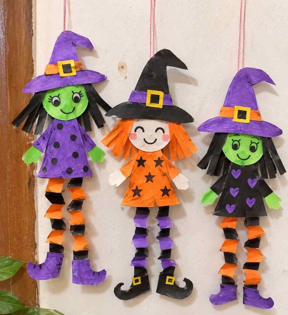21 Easy & Creative Fall Crafts for Kids to Make at Home 10 8. Easy Hanging Paper Witch Craft for Kids Make Halloween decorations extra playful with these cute hanging paper witches! Their colorful hats, funny faces, paper-strip hair, and zigzag accordion legs make them fun to display in a classroom, doorway, or kids’ room. This simple craft uses inexpensive construction paper and is easy to customize with different colors and expressions. Materials Needed: - Black, purple, orange, and green construction paper - White paper for the face - String or yarn - Glue stick - Child-safe scissors - Black marker or crayons How to Make It: 1. Cut a circle for the witch’s face and a simple dress shape from colored paper. 2. Make a pointed witch hat from black or purple paper, then add a small colored band and buckle. 3. Cut thin paper strips for the hair and glue them around the face. 4. Fold two long paper strips back and forth like an accordion to make zigzag legs. Attach them beneath the dress and add simple paper boots. 5. Draw a funny face, decorate the dress with dots or stars, and tape a piece of string to the back of the hat to hang the witch. Quick Tip: Make each witch a different color and give them silly expressions to create a fun Halloween display.