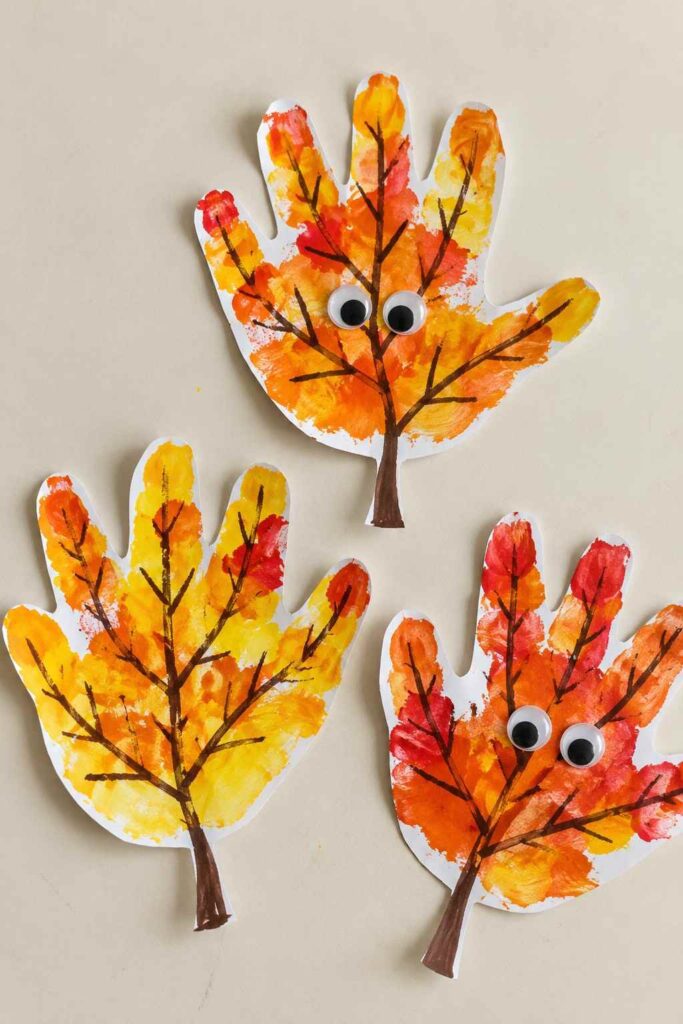 21 Easy & Creative Fall Crafts for Kids to Make at Home 19 17. Colorful Handprint Fall Leaves Craft for Kids
Turn little handprints into colorful autumn leaves! Kids can use yellow, orange, and red paint to create their own leafy designs, then add simple brown branches and googly eyes for a fun, friendly look. It's an easy fall art activity for preschoolers and kindergarteners.
Materials Needed:
- White cardstock or construction paper
- Yellow, orange, and red washable paint
- Brown marker or paint
- Googly eyes (optional)
- Paintbrush
- Child-safe scissors
- Glue stick
How to Make It:
1. Trace your child's hand on white paper and cut out the handprint shape.
2. Dab yellow, orange, and red paint over the fingers and palm, letting the colors mix naturally.
3. Once dry, draw a few brown leaf veins and a long stem with a marker.
4. Glue on two googly eyes to turn the leaf into a silly little fall character.
Quick Tip: Make handprints in different sizes and let kids mix the paint freely. Every leaf will turn out a little different!